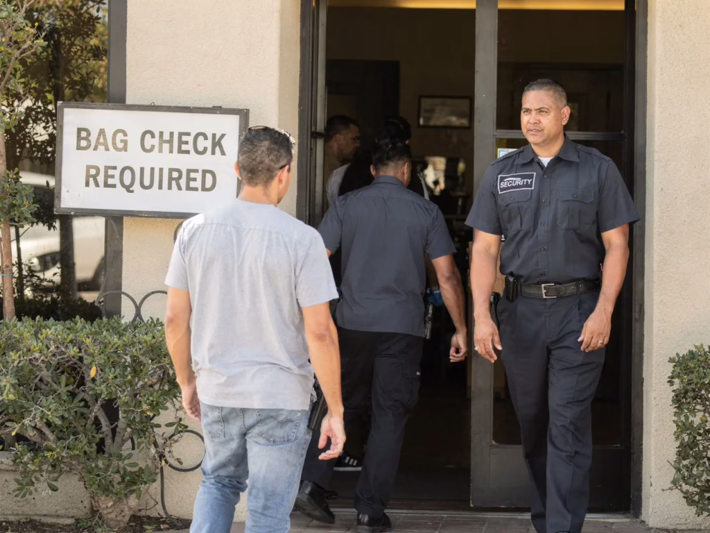 Security personnel at a bag check entrance, man waiting by the sign, entrance safety enforcement scene.