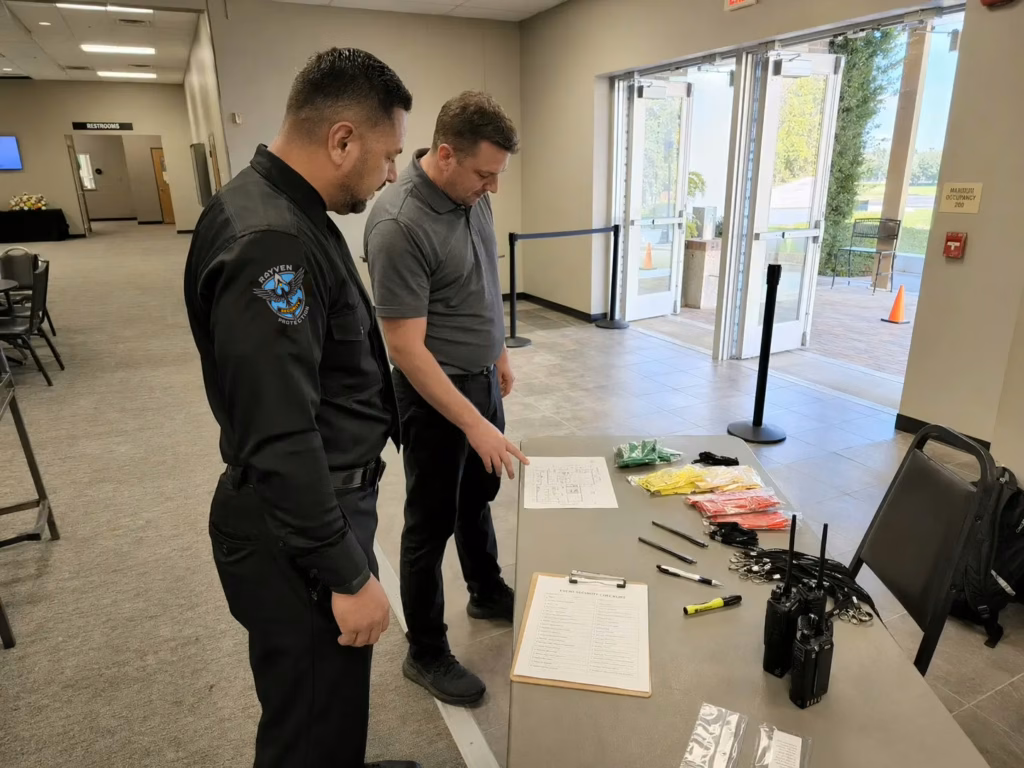Rayven Security Protection security guard and event staff member reviewing an event security checklist at a registration table inside a venue before guests arrive.